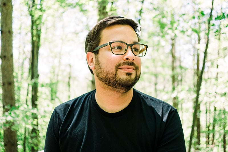 Bryan wearing glasses and a black shirt, with trees behind him.