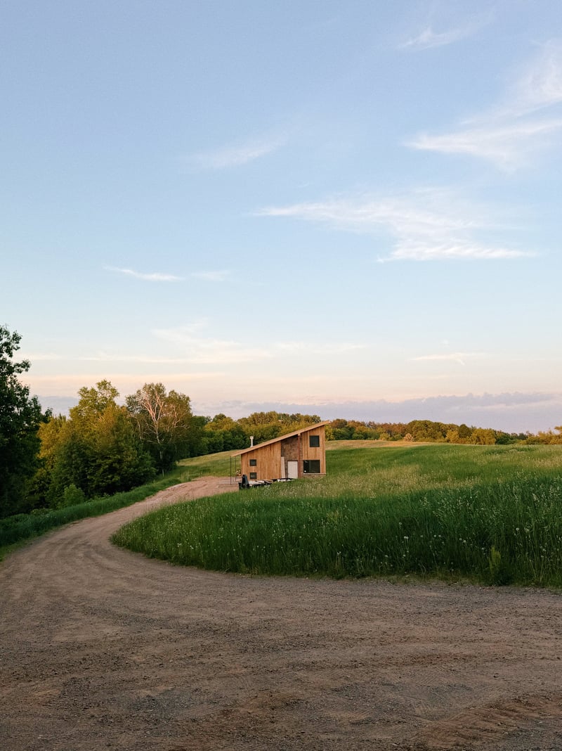 The Duck Inn, a wood-sided cabin with a sloping roof, in a grassy field at sunset.