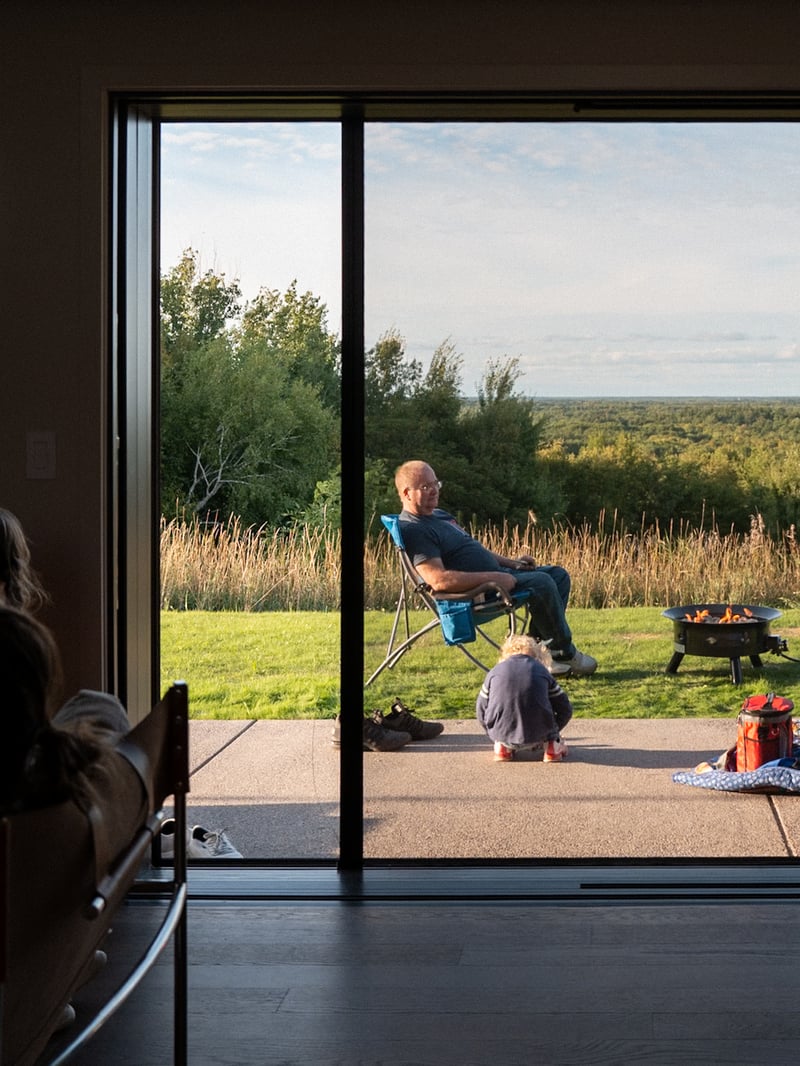 View through the cabin doorway onto the patio and surrounding meadow.