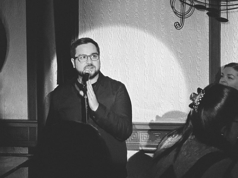 Black-and-white photo of Bryan singing into a microphone beside a pianist.